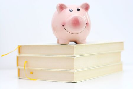 Piggy bank on top of pile of books suggesting saving for college conceptの写真素材