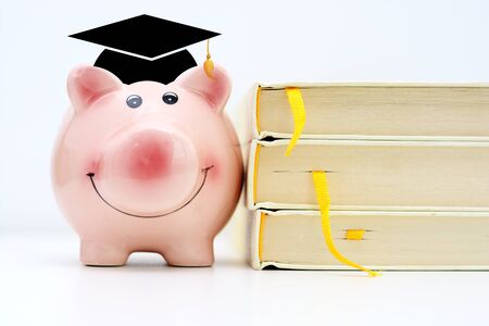 College fund concept with piggy bank standing near a pile of booksの写真素材