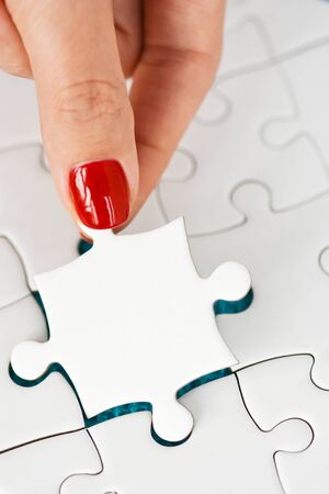 Woman hand fitting the right piece of puzzle suggesting business  networking conceptの写真素材