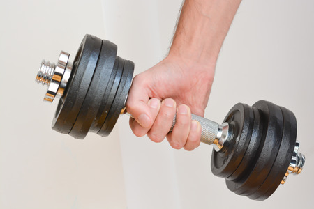 Young man doing exercises with dumbbells at homeの写真素材