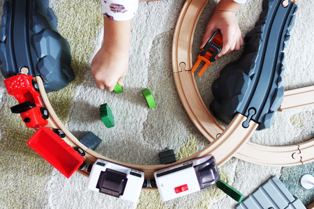 Little baby boy playing with colorful wooden train on the carpetの写真素材