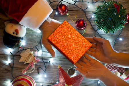 Santaâs hand offering a gift box to a woman in a traditional Christmas dÃ©corの写真素材