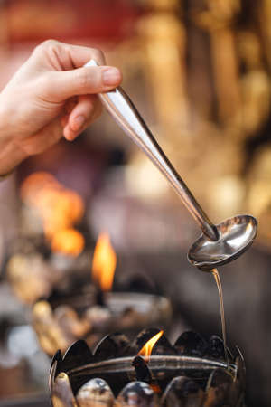 Oil filling in Thai style metal candle in Thai temple, Chiang Mai, Thailandの写真素材