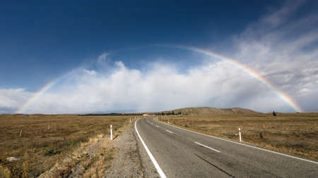 Beautiful full rainbow over road and mountain, New Zealandの写真素材