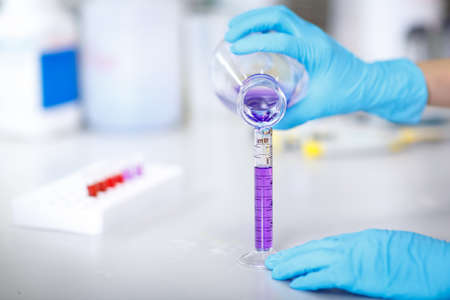 Decanting a violet liquid into a graduated cylinder in molecular laboratoryの写真素材