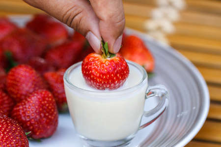 Strawberry in a cup of milk on bamboo tableの写真素材