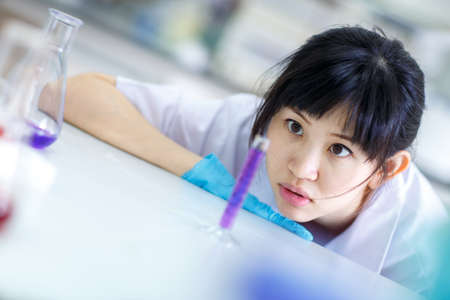 A young scientist looking pensively at tubing with liquidの写真素材