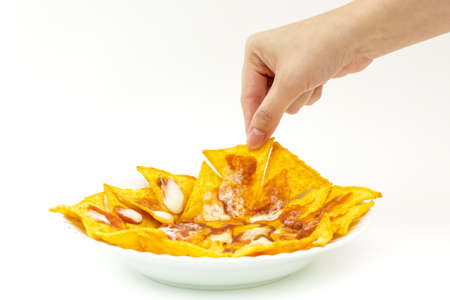 Pincking tortila chips covered with cheese (Nachos) from white dish on isolated white backgroundの写真素材
