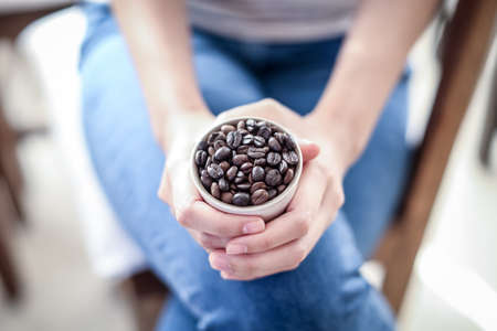 Coffee bean in cup on woman hand conceptの写真素材