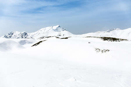 Skiers walking on snow covered mountain ranges, Tateyama, Japan