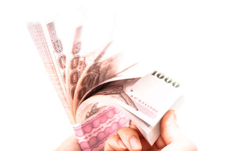 Woman hand counting pack of 1,000 Thai baht bank note on isolated white background