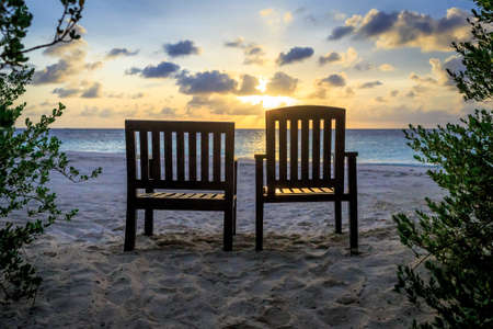 Couple of beach chair stand facing to ocean during sunset time, Maldivesの写真素材