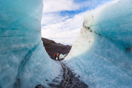 Hiker walking pass ice wall during hiking on glacier, Solheimajokull, Icelandの写真素材
