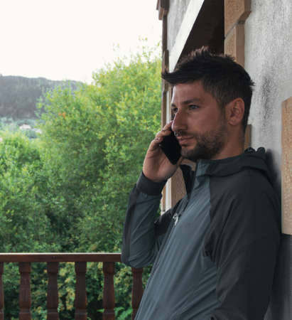 Young man leaning against the wall, talking on the mobile phone