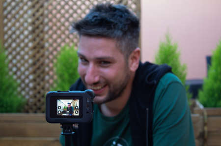 Social media influencer using camera to create content. man shooting video of himself outdoors
