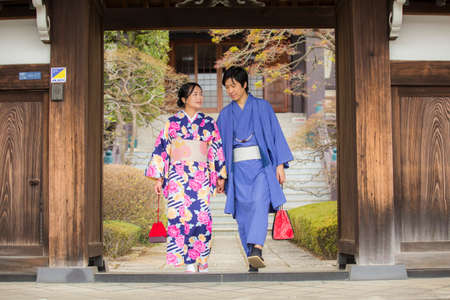 Tokyo, Japan- March 29,2019 an asian couple wearing traditional japanese clothes walking out from an old wood door frameのeditorial素材