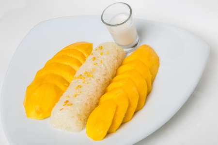 ripe mango sticky rice top with yellow bean serve with a shot of coconut sauce isolate white backgroundの写真素材