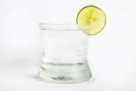 gin tonic in a glass decorated by sliced lime white backgroundの写真素材