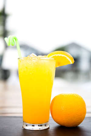 fresh orange juice in glass with straw decorated with sliced of orange put on a wood table depth of field backgroundの写真素材