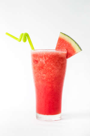 red watermelon smoothie in a tall glass decorated with piece of watermelon white backgroundの写真素材