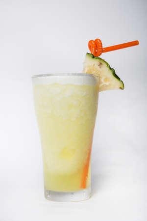 yellow pineapple smoothie with straw in a tall glass decorated with a piece of pineapple isolated white backgroundの写真素材