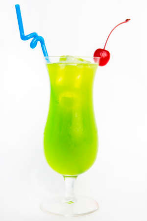 green drink in a tall glass decorated with cherry and straw white backgroundの写真素材