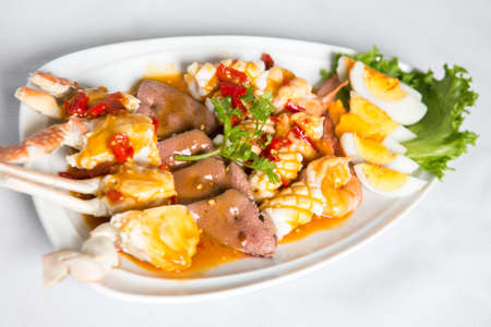 scald seafood served with thai spicy sauce and cutting boiled eggs served in white plateの写真素材