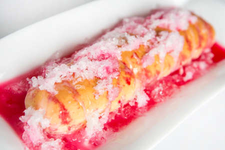 thai dessert called ' ka nom pang yen' bread top with red syrup and ice top with condensed milk served on white plateの写真素材