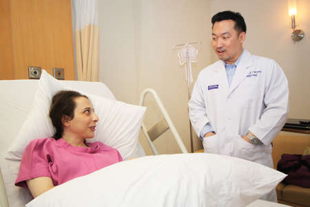 Bangkok, Thailand - September 20,2011 an asian guy doctor is talking to western woman patient who is lay down on bedのeditorial素材