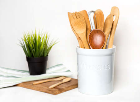 Bangkok, Thailand April 21,2020 white utensil holder ceramic decorated with wood cutting board and small wood spoon and fork in white background on the tableのeditorial素材
