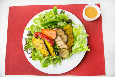 vegetable salad top with shrimps and grilled sliced oringi mushroom in white plate  served with thousand island dressing in a dipping bowl on a red placematの写真素材