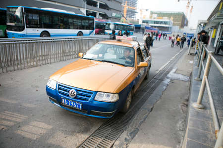 Changsha, China - Feb 20,2014 a yellow navy blue chinese taxi driving slowly on the roadのeditorial素材