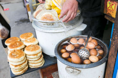 Changsha, China Feb 20,2014 : asian street food styles boiled eggs in a hot pot and stack fried pancakes with a steamed corn on the sideのeditorial素材