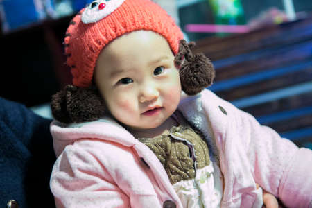 Changsha,China Feb 20, 2014 : cute kid wearing a wool knitting hat beanie and pink sweater jacket looking at the cameraのeditorial素材