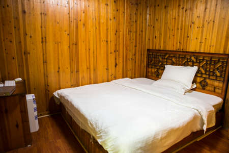 Changsha,China Feb 20, 2014 a wooden bedroom with a king size bed, white sheet and pillow decorated chinese styles.のeditorial素材