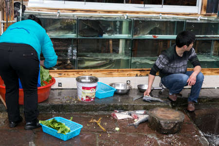 FengHuang, China Feb 21,2014 asian people are preparing fish and green vegetables on street for opening shopのeditorial素材