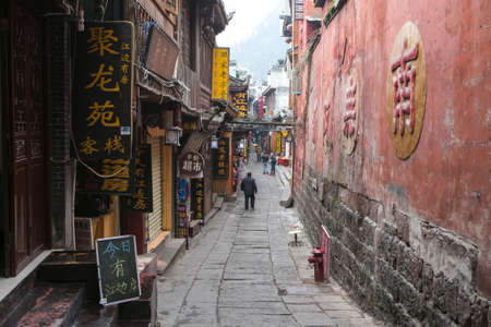 FengHuang,China Feb 21,2014 a narrow street in Fenghuang village red wall with chinese characters and shops with chinese character signsのeditorial素材