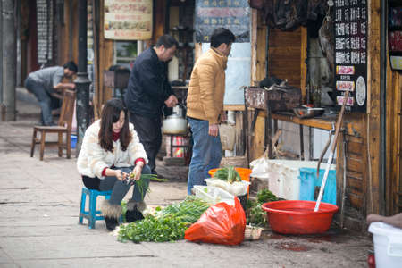 FengHuang, China Feb 21,2014 an asian female is preparing green vegetables on street for shop opensのeditorial素材