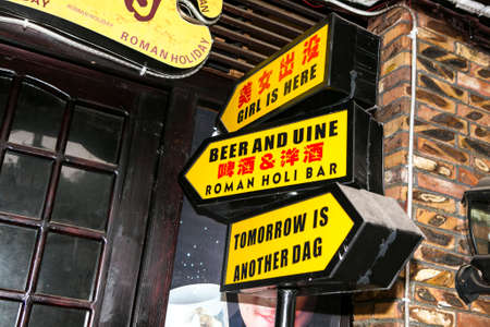 FengHuang-China, Feb 21, 2014 : bright yellow signs arrow direction written in english and chinese text in front of the shopのeditorial素材