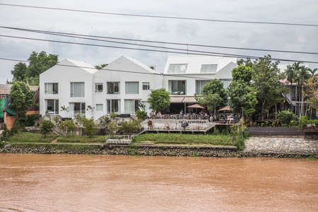 Ayutthaya, Thailand - 16 August 2020: big white modern buildings with a big terrace where are people having a meal with river viewのeditorial素材