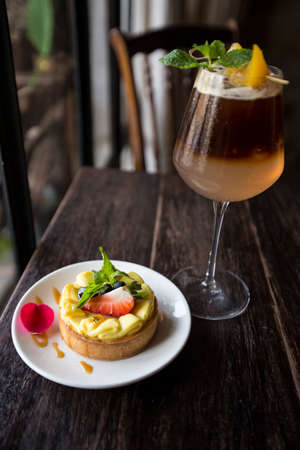 Lemon tart with fresh strawberry and soda serve on dark wooden tableの写真素材