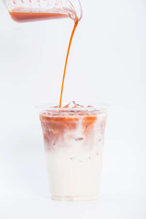 Pouring tea mixed with sweetened condensed milk on whiteの写真素材
