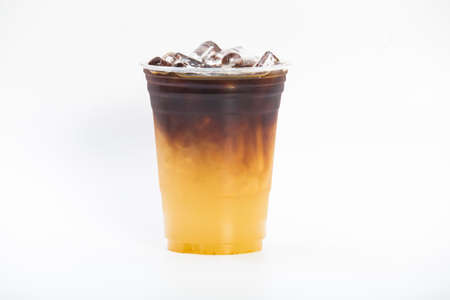 iced orange espresso, sour syrup of yuzu mixed with sweet honey at the bottom of a plastic cup top with concentrated espresso coffee shot isolated white backgroundの写真素材