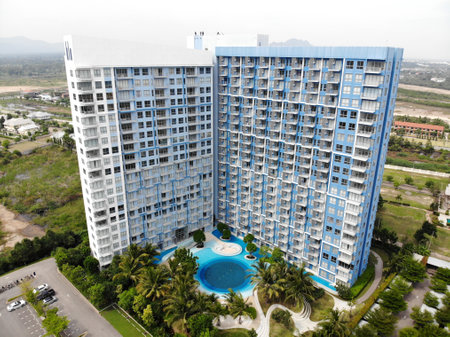 Prachuap Khiri Khan, Thailand-November 10, 2020: drone view of blue and white condominium where has a pool in a middle of an apartment an surrounding by trees and green spaceのeditorial素材