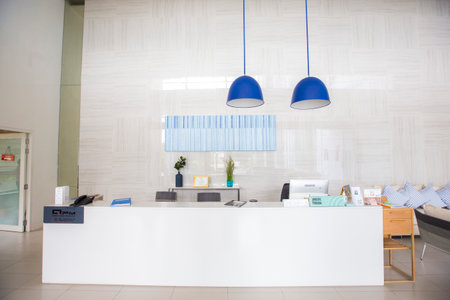 Prachuap Khiri Khan, Thailand-November 10, 2020: reception area long white counter bar decorated by blue hanging lamps and abstract picture frame on a wallのeditorial素材