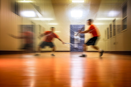 An action-packed scene of a racquetball game, the players moving so fast they're just a blur against the backdrop of the vivid courtの素材
