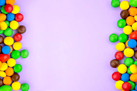 small colored candies on the sides on a purple backgroundの写真素材