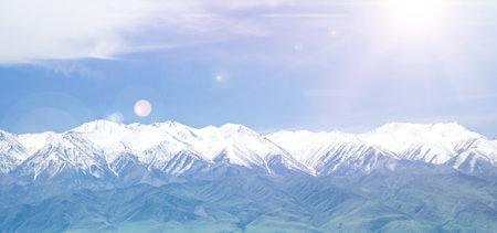 snowy mountains background with clouds and sun raysの写真素材