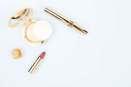 on a blue background cosmetics in a gold case lipstick, mascara and powderの写真素材