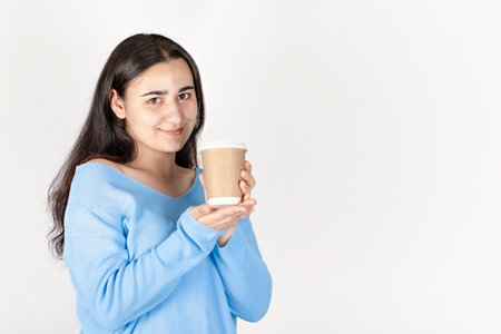 portrait of a girl in a blue jacket with a glass of coffee on a light background